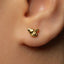 A close-up of a person's ear with a small gold earring in the earlobe.