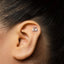 A small silver earring with a miniature golf cart design is visible in the person's ear.