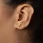 A close-up of a person's ear with a small gold earring in the earlobe.