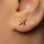 A close-up of a person's ear with a small gold earring featuring a cross-like symbol.