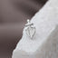 A silver cross-shaped pendant with a shield-like design, resting on a white surface.
