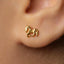 A close-up of a person's ear wearing a small gold earring shaped like a horse.