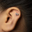 A close-up of a person's ear with a small silver earring in the shape of a horse.