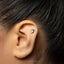 A close-up of a person's ear with a small silver earring in the earlobe.