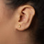 A close-up of a person's ear with a small gold earring in the earlobe.