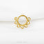 A gold-colored ring with a circular design featuring heart-shaped and heart-shaped holes, placed on a white background.
