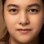 A close-up portrait of a young woman with a gold nose ring, her eyes looking directly at the camera.