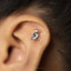 A small, silver earring in the shape of a bird is visible in the person's ear.