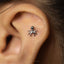 A close-up of a person's ear with a small silver spider-shaped earring inserted.
