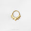 A gold-colored ring with a unique, abstract design is shown against a white background.