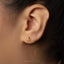 A close-up of a person's ear with a small gold-colored earring featuring an octopus design.