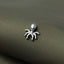 A small silver metal insect figurine is resting on a textured green fabric surface.