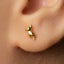 A close-up of a person's ear with a small gold earring featuring a small animal design.