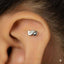 A silver earring with a mask-like design is visible in the person's ear.