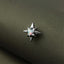 A close-up image of a star-shaped metal pin with a gemstone in the center, resting on a textured fabric surface.