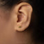 A close-up view of a person's ear with a small gold-colored earring featuring a butterfly design.