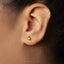 A close-up of a person's ear with a small gold earring featuring a small animal design.