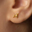 A close-up of a person's ear wearing a small gold-colored earring with a small animal design.