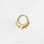 A gold-colored ring with a unique, abstract design is shown against a white background.