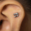 A close-up of a person's ear with a small, silver-colored metal object, possibly an earring, inserted into the ear.