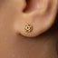 A close-up view of a person's ear with a small gold earring featuring a star-shaped design.