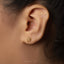 A close-up view of a person's ear with a small gold earring featuring a star-shaped design.