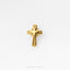 A single, shiny gold cross pin against a white background.