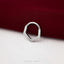 A silver ring with a unique, textured design is resting on a red fabric surface.
