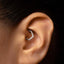 A close-up of a person's ear with a diamond-encrusted earring visible.