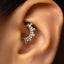 A close-up of a person's ear with a decorative piercing, specifically an earring with a floral design.