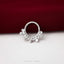 A silver ring with a decorative design is placed on a red fabric surface.