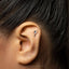 A close-up of a person's ear with a small silver earring in the earlobe.