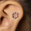 A silver earring with a circular design and small star-shaped embellishments is visible in the image.