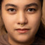 A close-up portrait of a woman with a nose piercing, looking directly at the camera.
