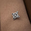 A silver metal pin with a unique, intricate design is resting on a textured fabric surface.