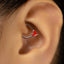 A close-up of a person's ear with a heart-shaped earring in the earlobe.
