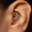 A close-up of a person's ear with a silver ring or earring in the earlobe.