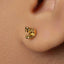 A close-up of a person's ear with a small gold earring in the earlobe.