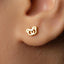 A close-up view of a person's ear adorned with a small gold earring featuring a heart-shaped design.