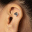 A silver earring with a snake design is visible in the person's ear.