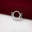 A silver ring with heart-shaped holes is displayed against a burgundy fabric background.