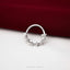 A silver ring with spikes protruding from it, placed on a red fabric surface.