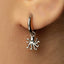 A close-up view of a person's ear with a silver earring featuring an octopus charm hanging from it.