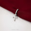 A silver cross-shaped charm is hanging from a red fabric, with the text "SHEMISLIJ JEWELS" visible below the image.