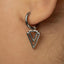A close-up view of a person's ear adorned with a silver earring featuring a triangular design.