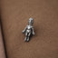 A small silver figurine is placed on a textured brown surface.