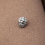 A small silver bead or ornament is resting on a textured fabric surface.