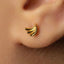 A close-up view of a person's ear with a small gold earring featuring a banana design.