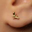 A close-up of a person's ear with a small gold earring featuring a leaf design.
