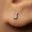 A close-up of a person's ear with a small silver letter "J" earring in the earlobe.